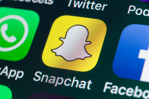 Close-up of the Snapchat app icon on a smartphone screen alongside other social media icons.
